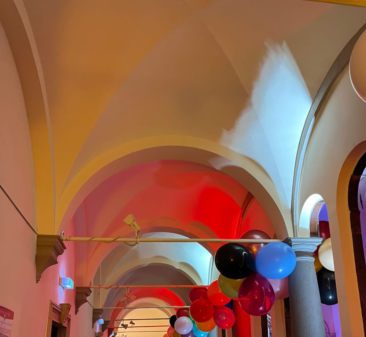 Umsetzung: Gewölbe in Rot, Weiß und Gelb beleuchtet, mit Ballondekoration